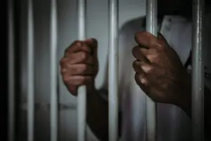 hands of man on prison bars