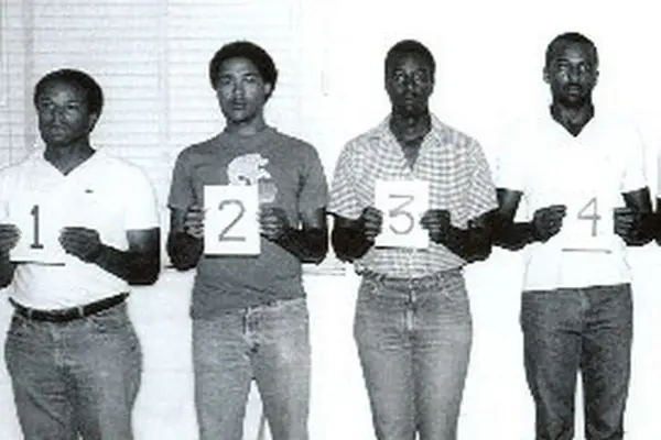 four men standing in a line holding up numbers 1 through 4