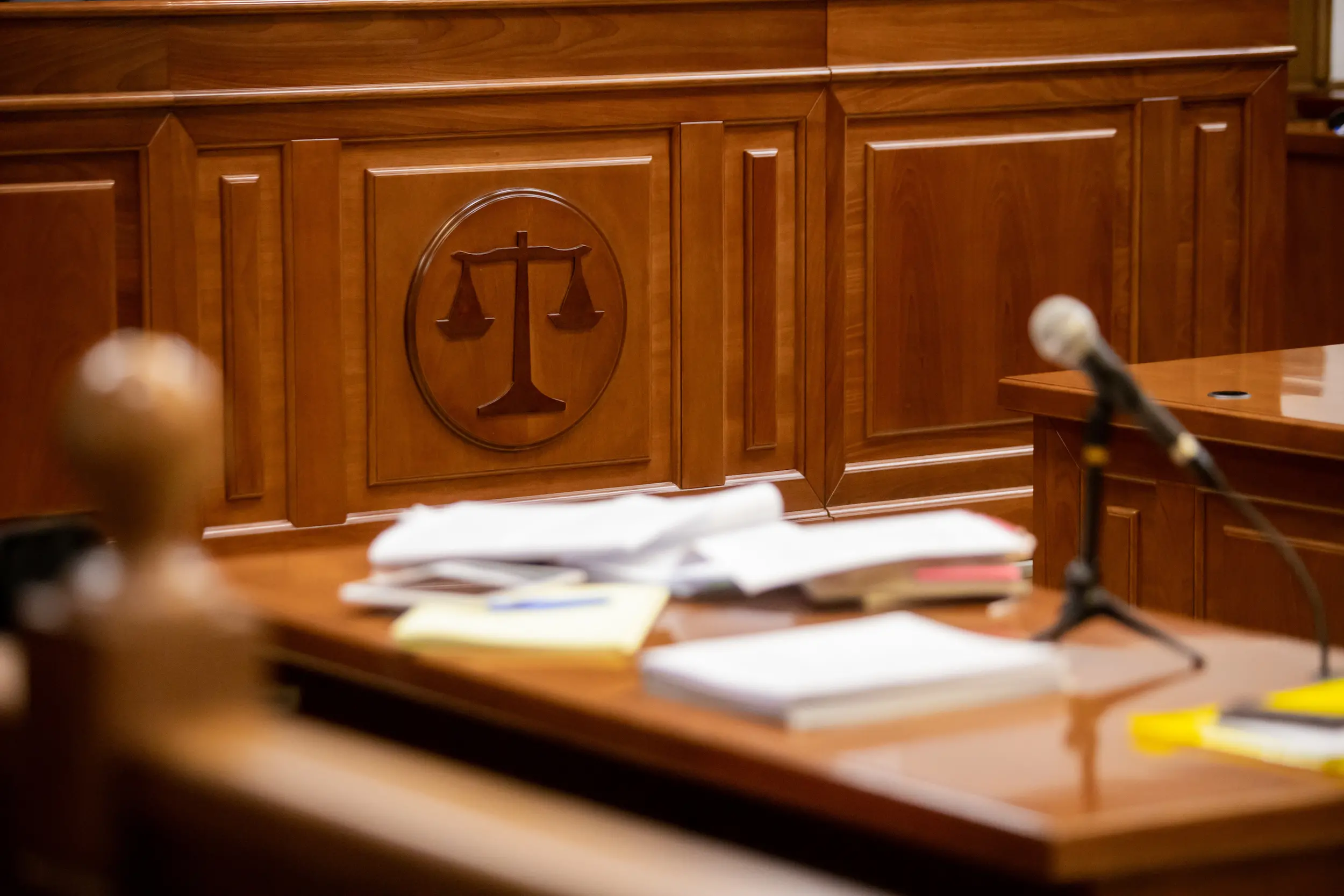 interior courtroom with a table of papers in the foreground. no people are shown