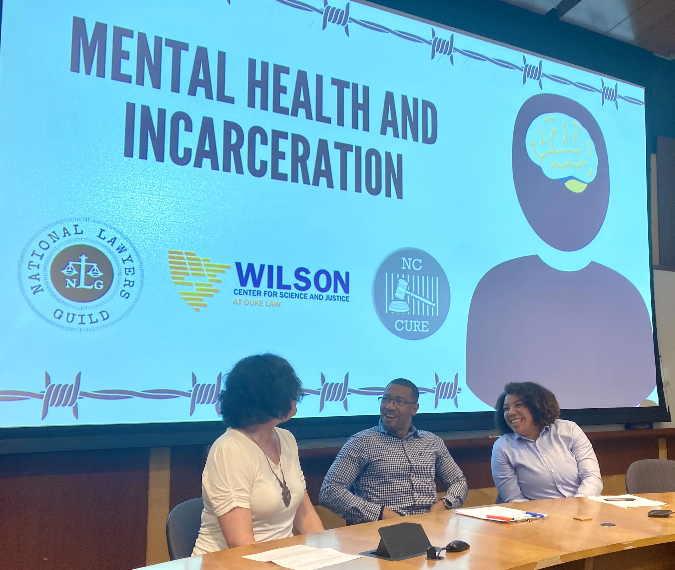 three people on a panel in front of a screen that says "Mental Health and Incarceration"