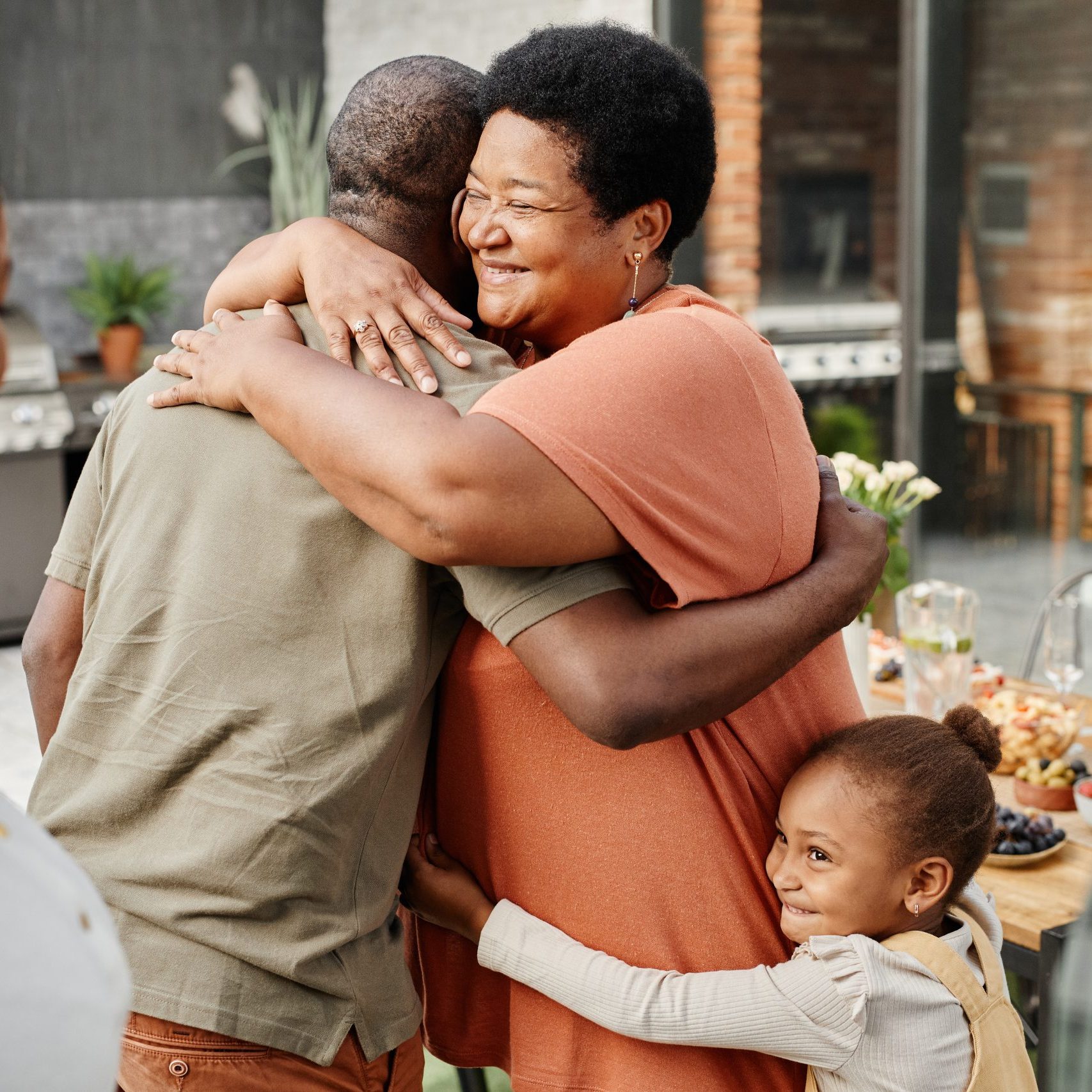 Senior Woman at Family Gathering Woman embracing man while a little girl embraces her